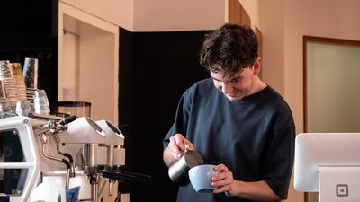 CMAG Barista pouring a coffee in the cafe