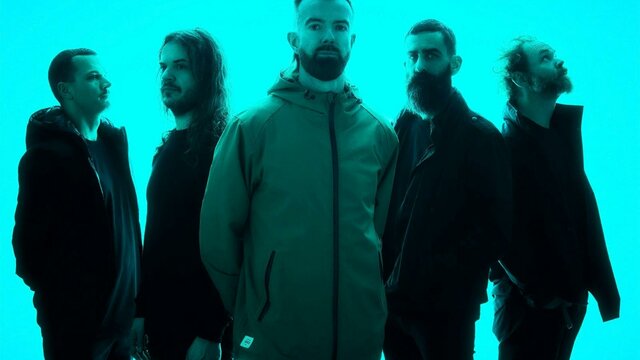 The five members of Karnivool in a neone blue background looking different ways off camera.