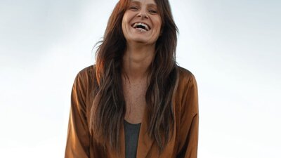 A photograph of a smiling woman with a guitar.