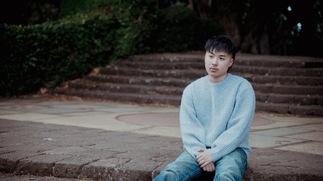 Keenan Te sitting on concrete looking off in the distance