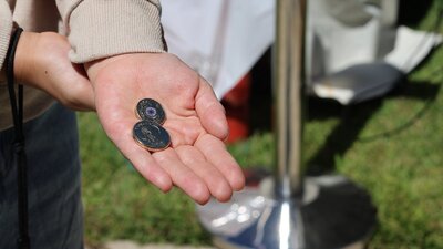 a hand holding 2 traded coins at the Mint