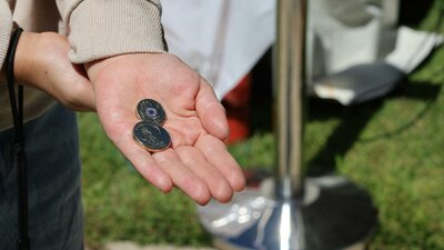a hand holding 2 traded coins at the Mint