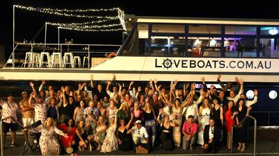Large groups of cheering people standing next to a big boat called Love Boat Canberra