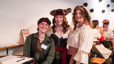 Three people in pirate outfits smile at the camera