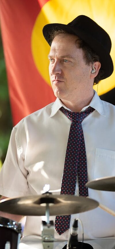 Drummer playing with Aboriginal flag in the background