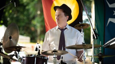 Drummer playing with Aboriginal flag in the background