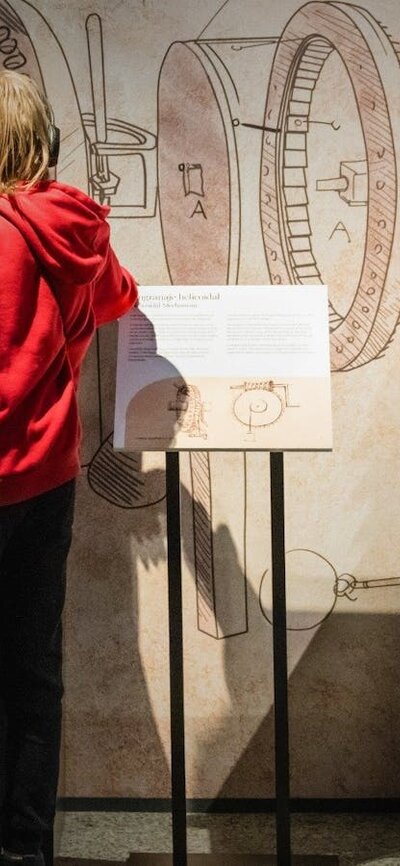 Visitor explores Leonardo da Vinci–inspired machines and sketches in an immersive exhibition.
