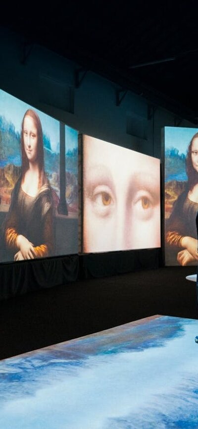 Visitors move through a digital gallery surrounded by immersive Mona Lisa projections.