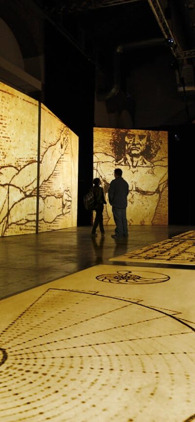 Visitors explore towering projections of Leonardo da Vinci’s sketches in an immersive gallery space.
