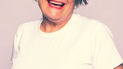 Woman smiling wearing white top and bright red lipstick