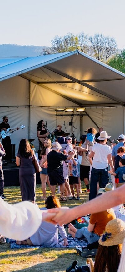 Two women running moving towards Live at Lanyon stage to dance, one looking back at camera
