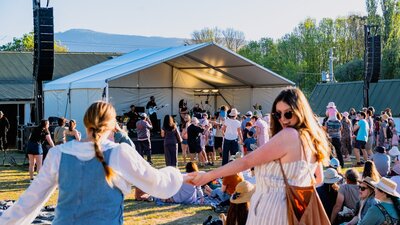 Two women running moving towards Live at Lanyon stage to dance, one looking back at camera