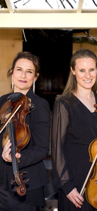 CSO musicians Kirsten Williams and Lucy Carrigy-Ryan posing holding their instruments at Lanyon.