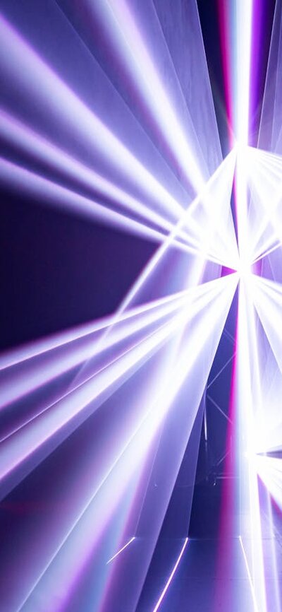 Still from Triptych by Robin Fox showing purple laser projections. Fox is visible in the frame.