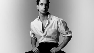 Black and white photo of comedian Louis Hanson in a white shirt and black pants