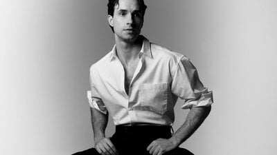 Black and white photo of comedian Louis Hanson in a white shirt and black pants