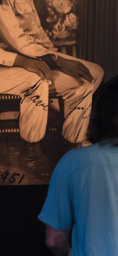 Man observes photograph of two men, one sitting on the others lap in the LOVING exhibition at CMAG