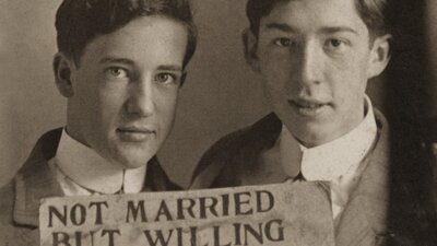 Two men holding a sign that reads 'NOT MARRIED BUT WILLING TO BE.'