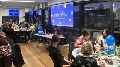 People sit around tables having fun while answering trivia questions