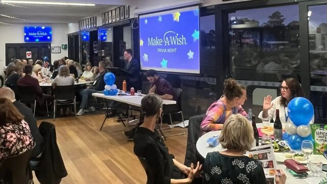 People sit around tables having fun while answering trivia questions