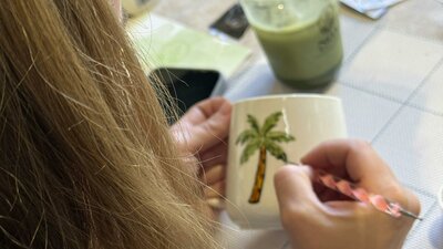 Guest hand-painting a ceramic cup at a NOA Matcha workshop