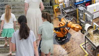 Three children with a guide and titan the robot pouring coins