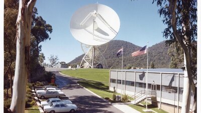 Photograph of a building with Australian and USA flags out the front, with a large satellite dish