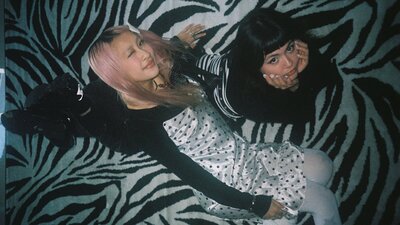 A photograph of two women sitting down in a background of zebra fabric