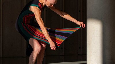 bald woman holds out striped skirt