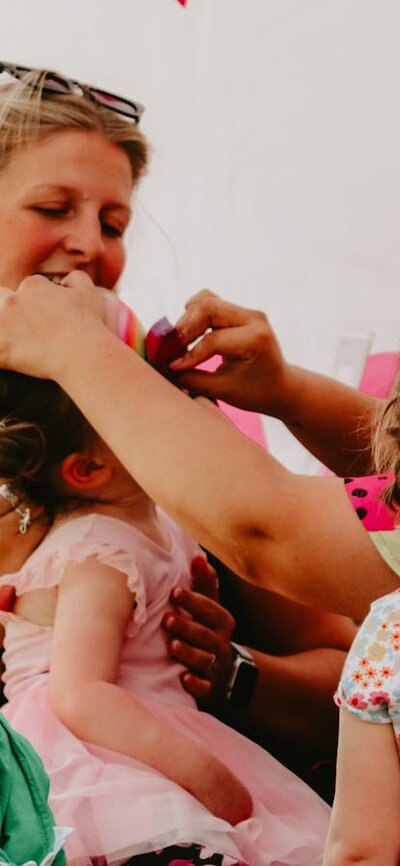 Children getting their facepainted whilst a smiling woman watches on