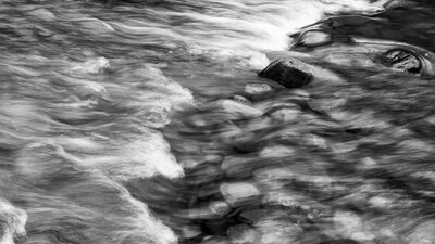 A black and white photo of waves crashing on a rocky beach.