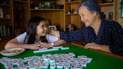Kieu Chinh (MRS CHEONG) and Nia Rush (ISABELLA) looking at each other fondly over mahjong