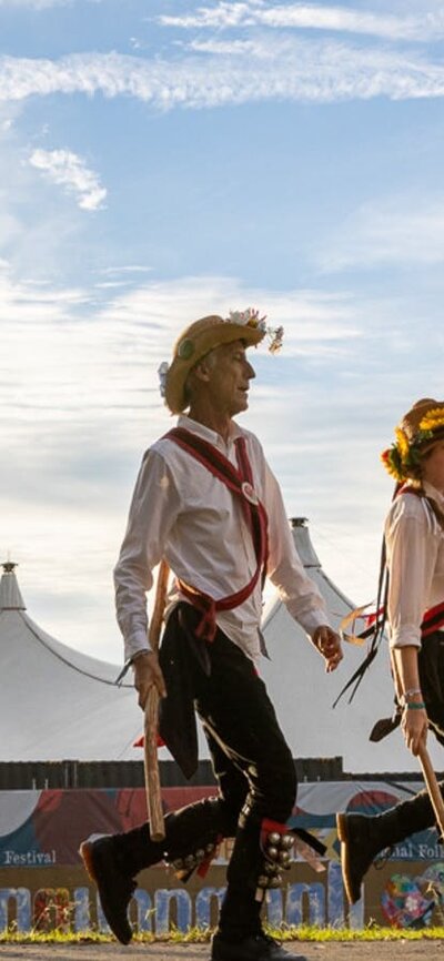 6 Morris Dancers perform in Traditional Costume with a big-top tent in the background