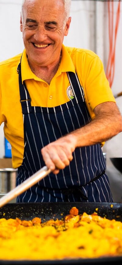 A man cooking paella in a large frying pan