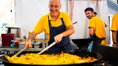 A man cooking paella in a large frying pan