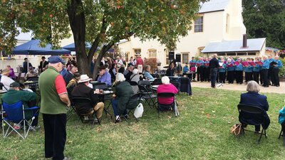 People seated outdoors watching choir.