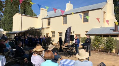 Come and inspect this building's initial Georgian style People seated outdoors with cream two storey building.