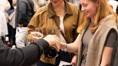 Young ladies having wine poured into their glass at the National Wine Festival tasting. Two ladies wine Tasting