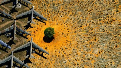 An aerial view of a desert landscape with multiple vintage military aircraft.