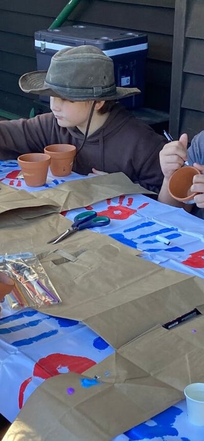 Kids gathered around a table enjoying a pot painting arts and craft activity