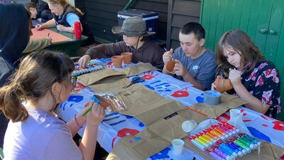 Kids gathered around a table enjoying a pot painting arts and craft activity