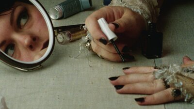 woman painting her nails with reflection of her face in a mirror