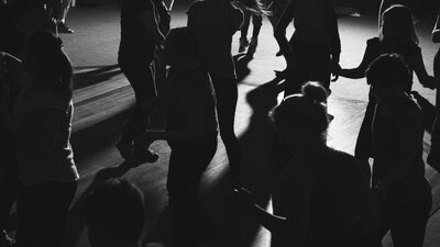 A group of silhouetted dancers on a dark dance floor