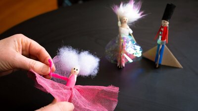 Person making nutcracker peg dolls created using craft materials