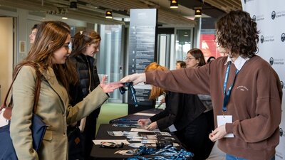 Two attendees collecting their conference lanyards from staff at a registration table