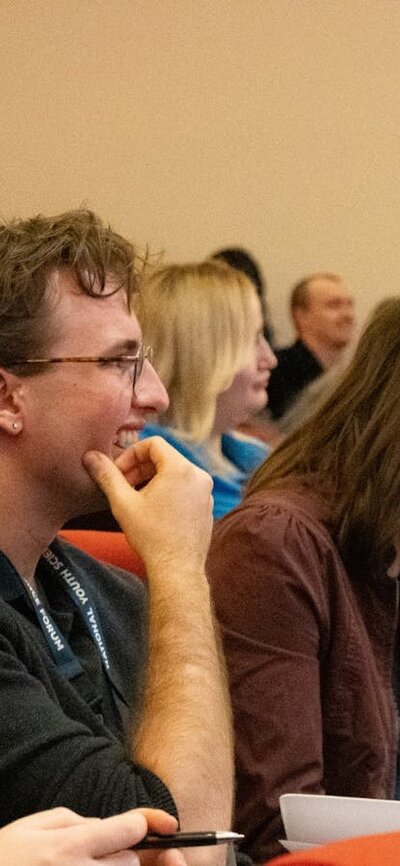 A row of conference attendees, two attendees are seen smiling in the foreground