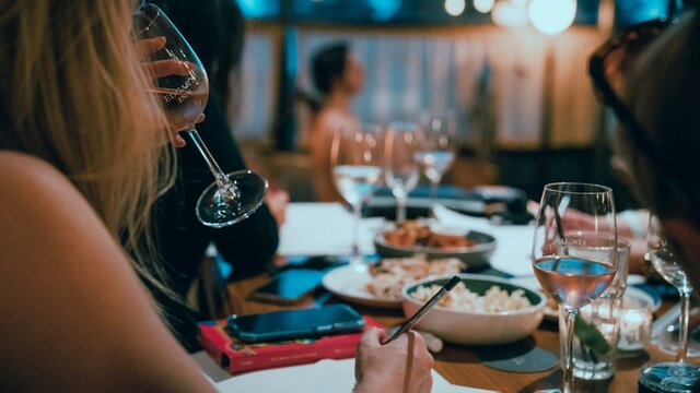 Woman drinking sparkling wine with art model sitting in background