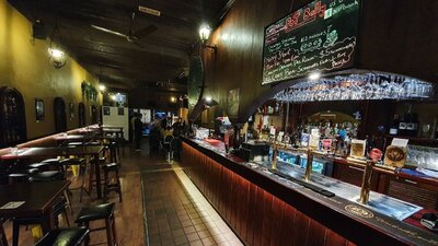 Row of bar tables and stools line the wall on the left, in front of a brightly lit bar on the right