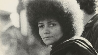 Black and white photo of a young woman with afro hairstyle staring straight at camera