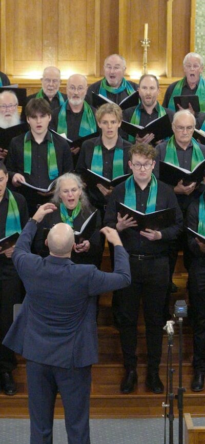 Female and male choristers singing, conducted by Dan Walker
